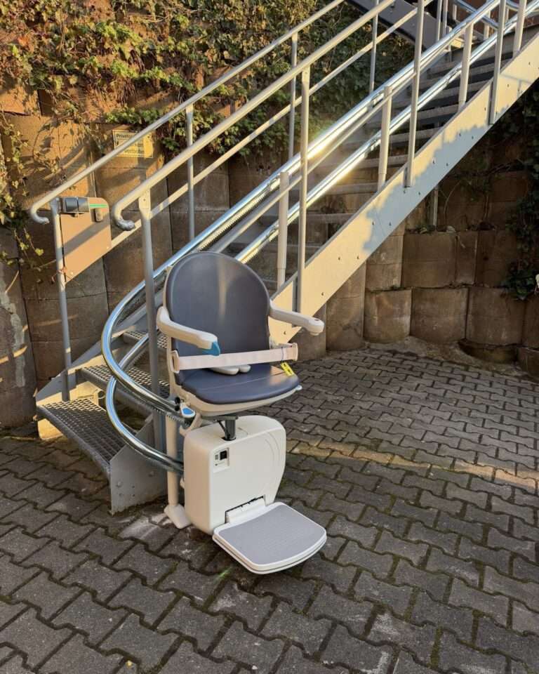 Projekte Wetterfester Außen-Treppenlift mit grauem Sitz und Doppelrohrschiene an einer Außentreppe aus Stahl in Niedernhall.