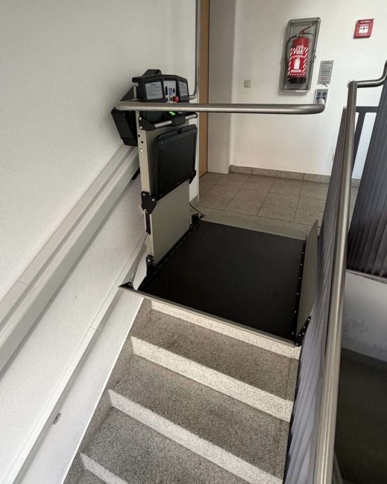 Projekte Blick von oben auf den fahrbereiten Plattformlift im Treppenhaus der US Army Barracks, der über die Steinstufen führt.