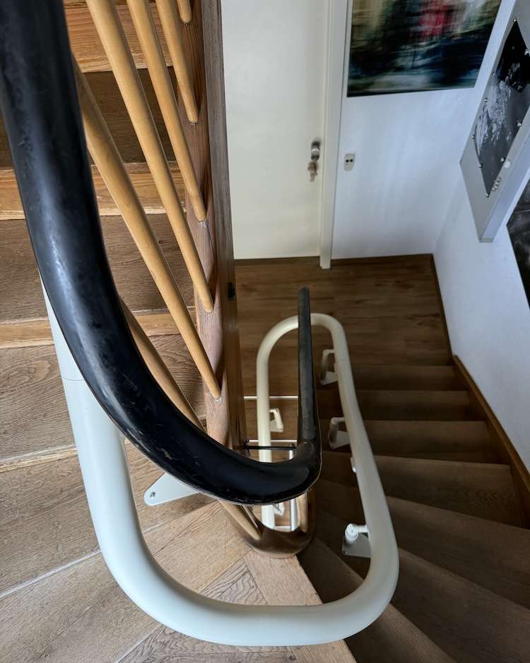 Projekte Draufsicht auf die weiße Einrohr-Schiene des Kurventreppenlifts, die eng am Geländer über zweieinhalb Etagen führt.