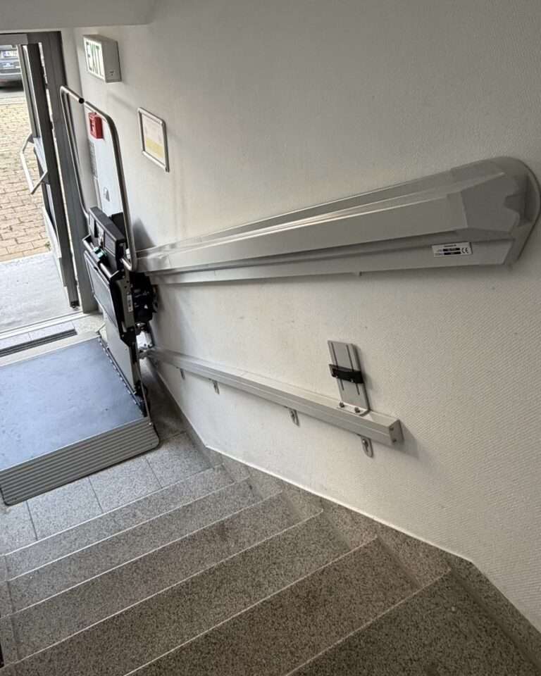 Projekte Detailansicht der an der Wand montierten Aluminium-Führungsschiene des Plattformlifts im Eingangsbereich.