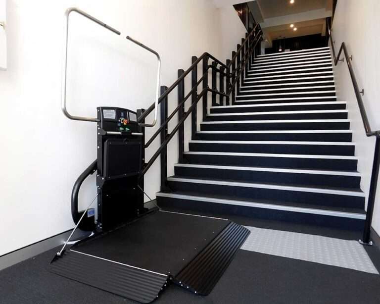 Montierter gerader Plattformlift von Paitsch-Lifte mit geöffneter Auffahrrampe am Fuß einer breiten Innentreppe.