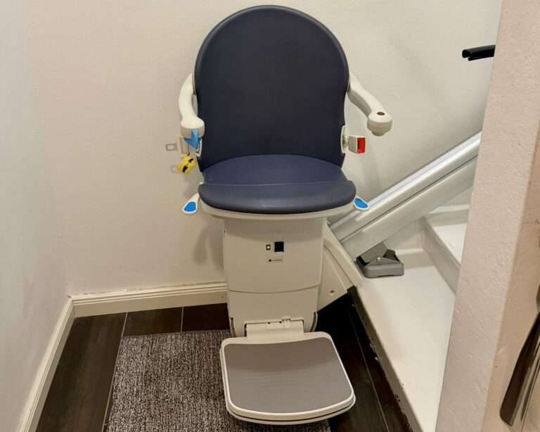 Montierter Handicare 1000 Treppenlift mit blauem Polstersitz auf einer geraden Treppe von Paitsch-Lifte.