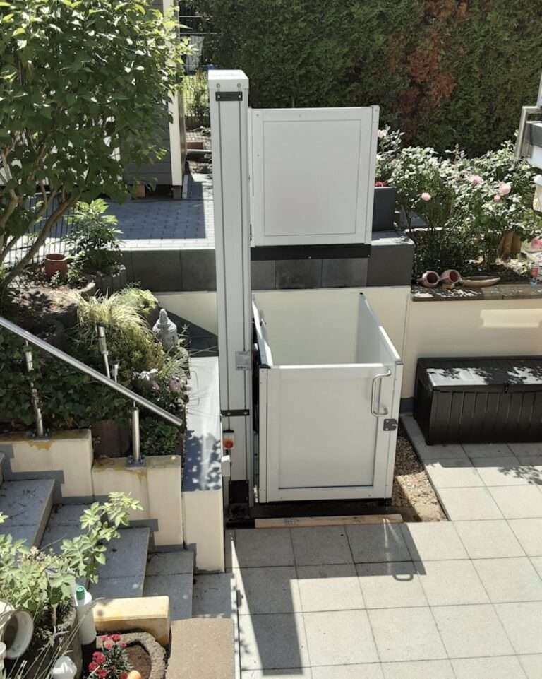 Weißer Hublift im Garten neben einer Außentreppe für den barrierefreien Zugang zur Terrasse