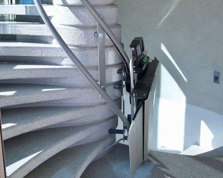 Eingeklappter kurviger Plattformlift von Paitsch-Lifte im Parkmodus an einer geschwungenen Steintreppe.