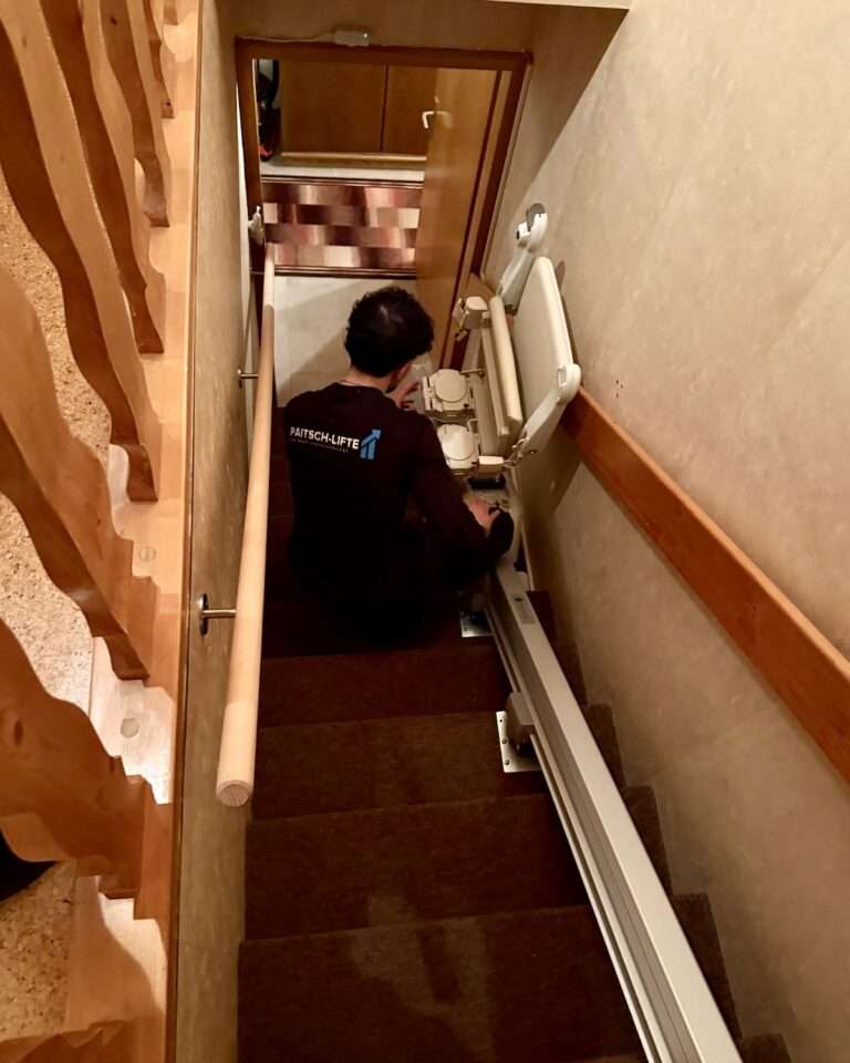 Servicetechniker von Paitsch-Lifte bei der fachgerechten Montage eines Treppenlifts auf einer steilen Innentreppe.