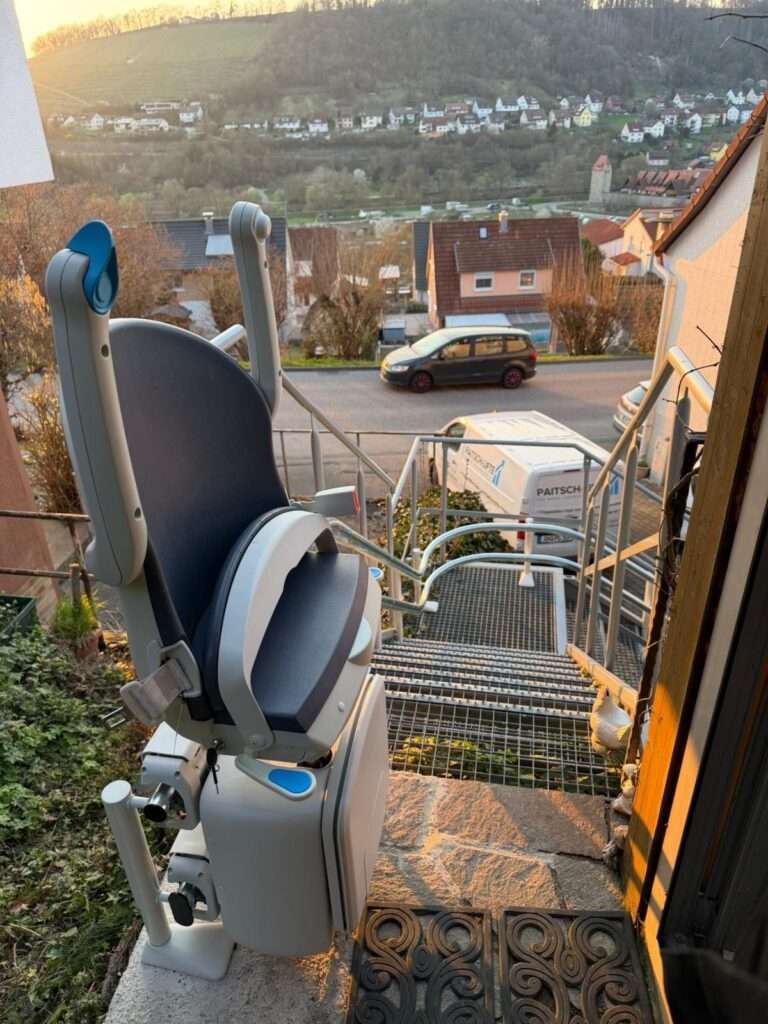 Moderner Sitztreppenlift für den Außenbereich auf einer Gitterrost-Außentreppe mit Blick ins Tal