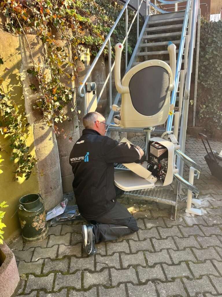 Servicetechniker führt Feineinstellungen an der Elektronik eines Außen-Treppenlifts durch