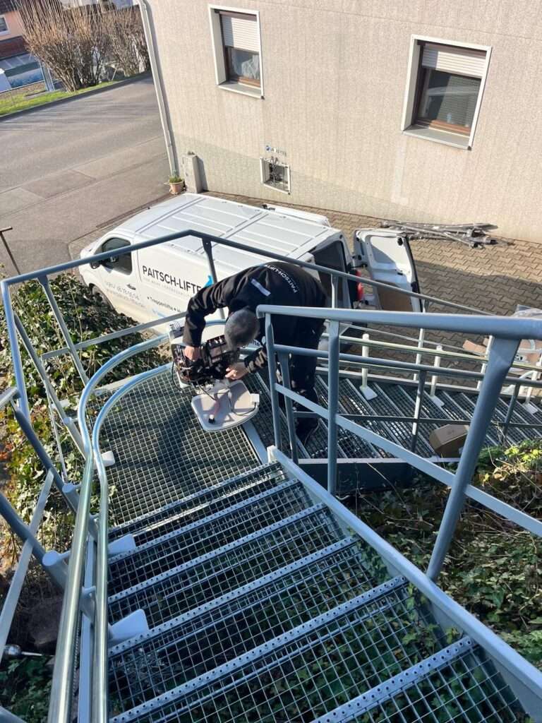 Techniker von Paitsch Lifte montiert einen Sitztreppenlift an einer Außentreppe